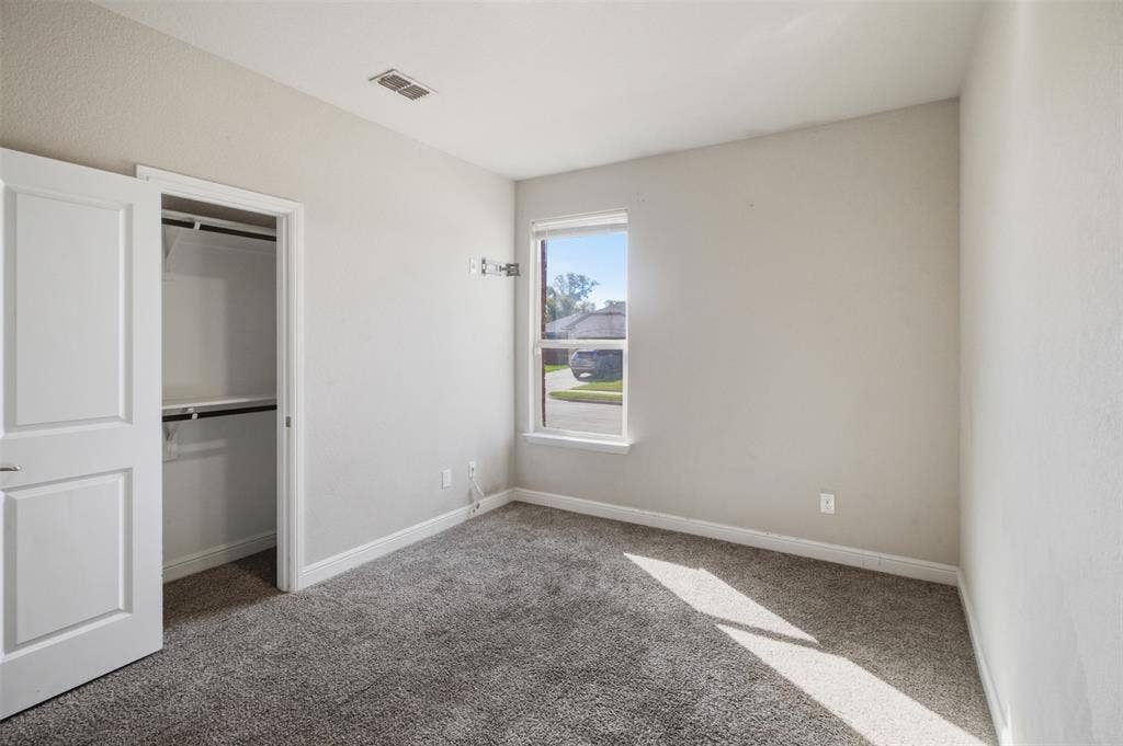 2513 Foules Drive, Glenn Heights, TX 75154 Wall-to-wall carpeting with built-in closet featuring bi-fold doors and shelving