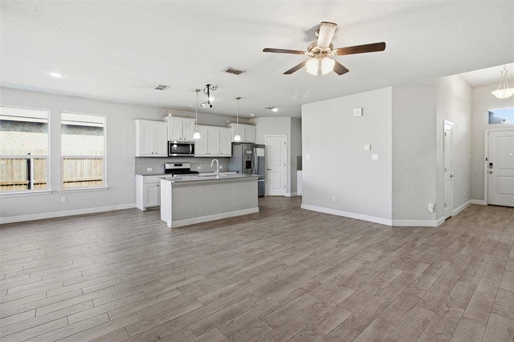2513 Foules Drive, Glenn Heights, TX 75154 Open-concept living space featuring wood-finish flooring, a contemporary kitchen island, white cabinetry, and stainless steel appliances
