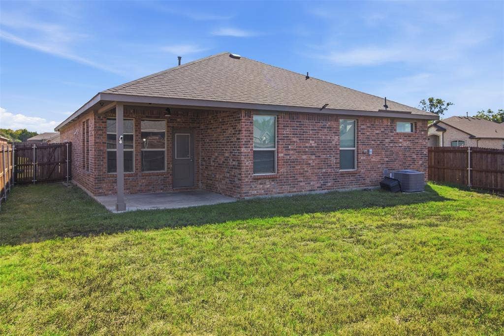 2513 Foules Drive, Glenn Heights, TX 75154 Brick exterior with covered patio, fenced yard, and multiple windows