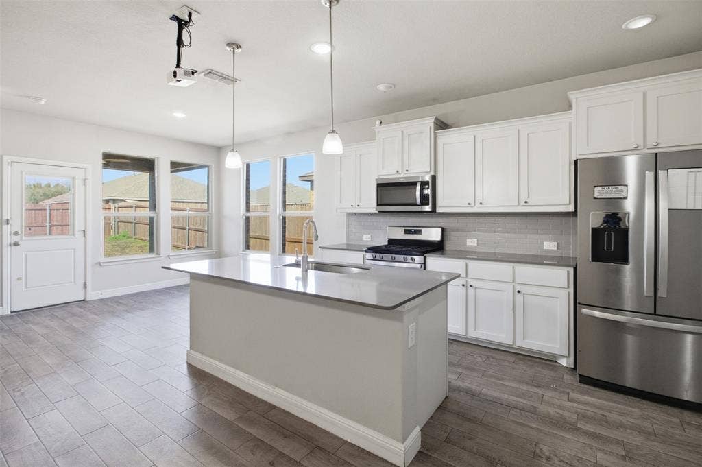 2513 Foules Drive, Glenn Heights, TX 75154 Kitchen featuring a center island, stainless steel appliances, white cabinetry, and wood-finish flooring