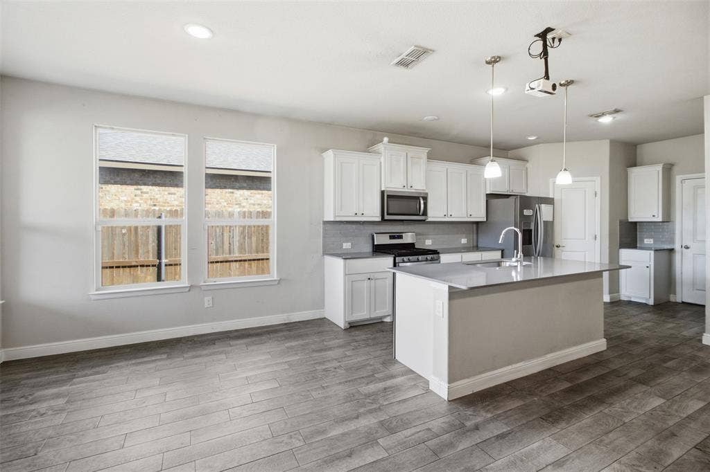 2513 Foules Drive, Glenn Heights, TX 75154 Open concept kitchen with a central island, stainless steel appliances, and white cabinetry