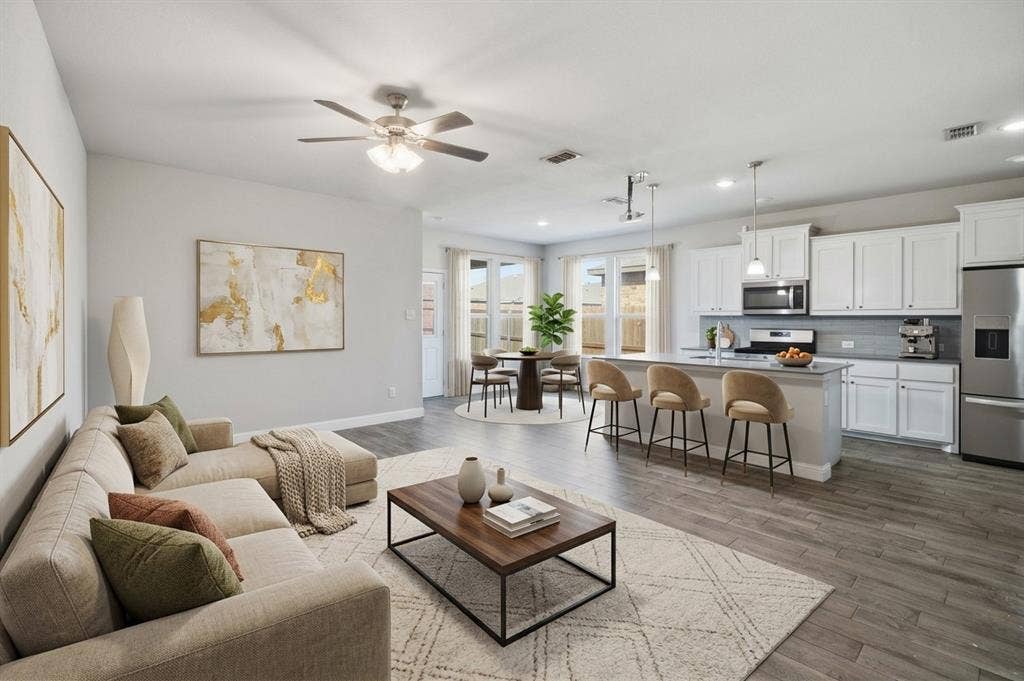 Open-concept kitchen featuring white shaker-style cabinetry, quartz countertops, a kitchen island, and  wood-look tile flooring