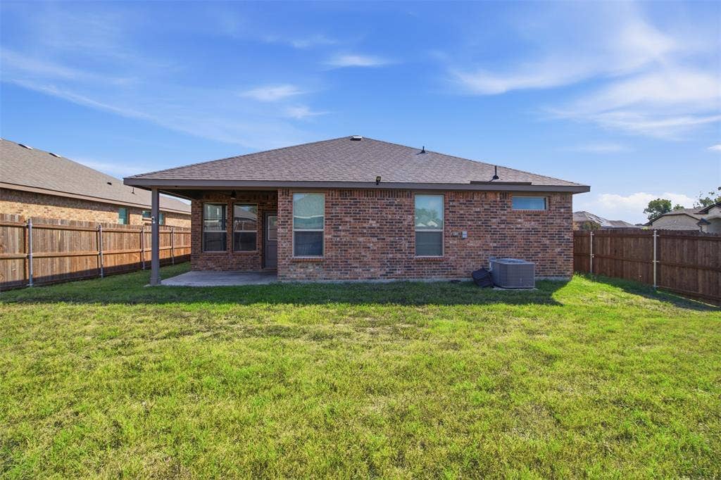 2513 Foules Drive, Glenn Heights, TX 75154 Expansive backyard featuring a covered patio, brick exterior, wood fence, and a pitched roof