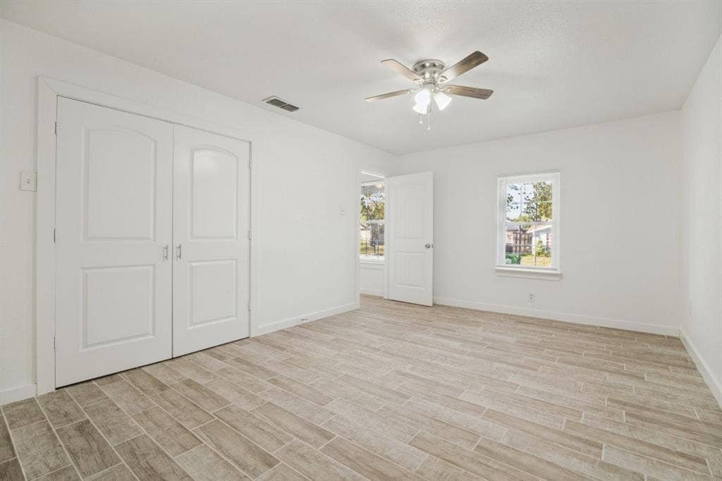 4420 Cochise Drive, Balch Springs, TX 75180 Wood-finish flooring, white walls, double-door closet, ceiling fan with light, and multiple windows