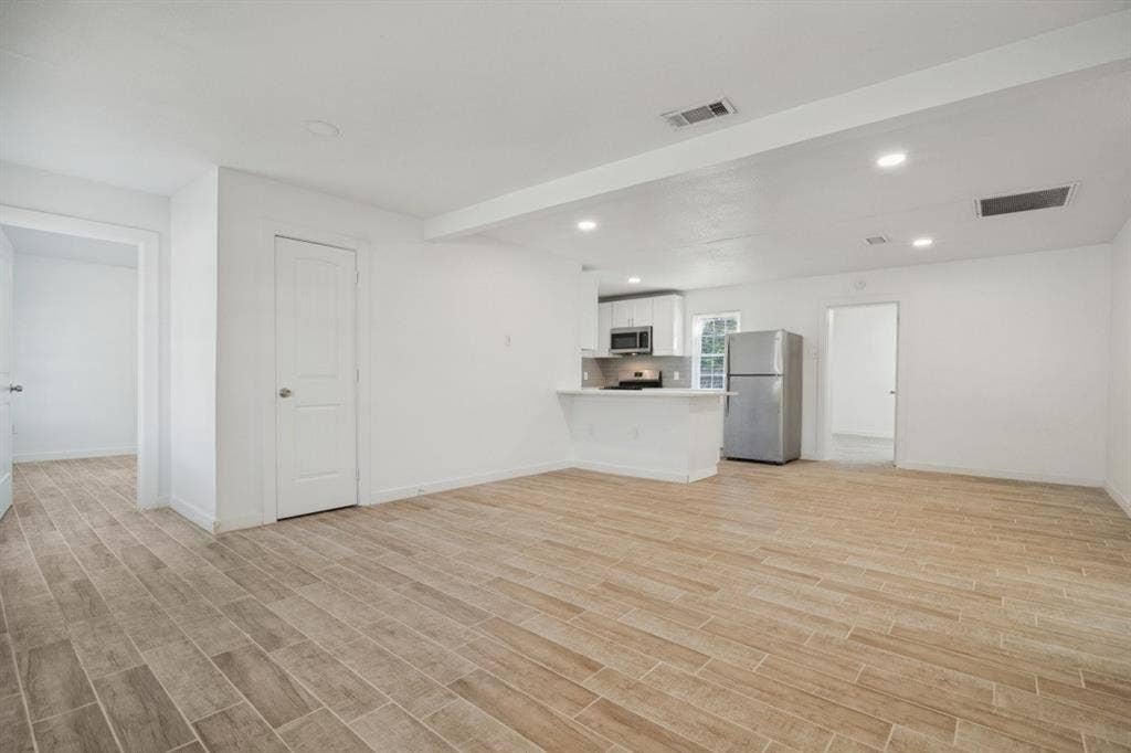4420 Cochise Drive, Balch Springs, TX 75180 Open-concept living area with wood-finish flooring, recessed lighting, and a kitchen featuring stainless steel appliances and white cabinetry