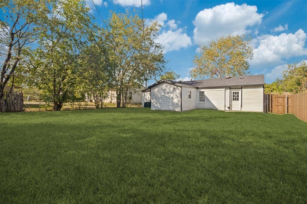 4420 Cochise Drive, Balch Springs, TX 75180 Expansive lawn with mature trees and a wood privacy fence