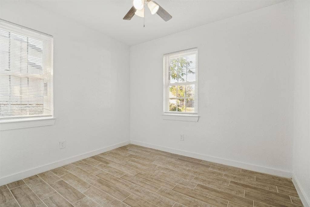 4420 Cochise Drive, Balch Springs, TX 75180 Wood-finish tile flooring, two windows with blinds, ceiling fan with integrated lighting, and white walls