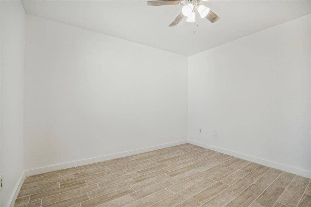 4420 Cochise Drive, Balch Springs, TX 75180 Wood-finish flooring with white baseboards, light neutral wall paint, and a ceiling fan with integrated lighting