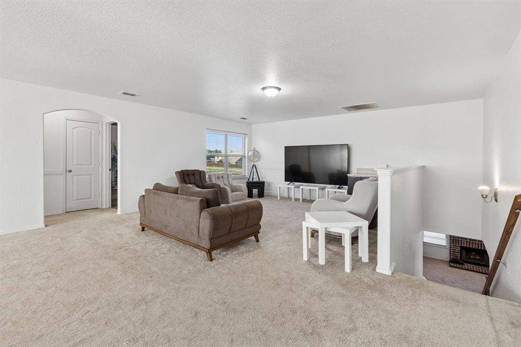 1501 Coyote Ridge Road, Wylie, TX 75098 Carpeted living area with white walls, an arched doorway, and built-in lighting