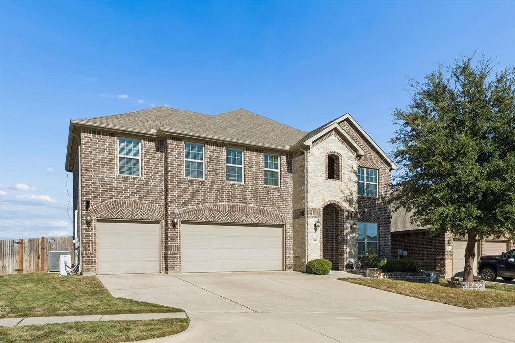 1501 Coyote Ridge Road, Wylie, TX 75098 Two-story brick exterior with stone accents, arched entry, two-car garage, and established front landscaping