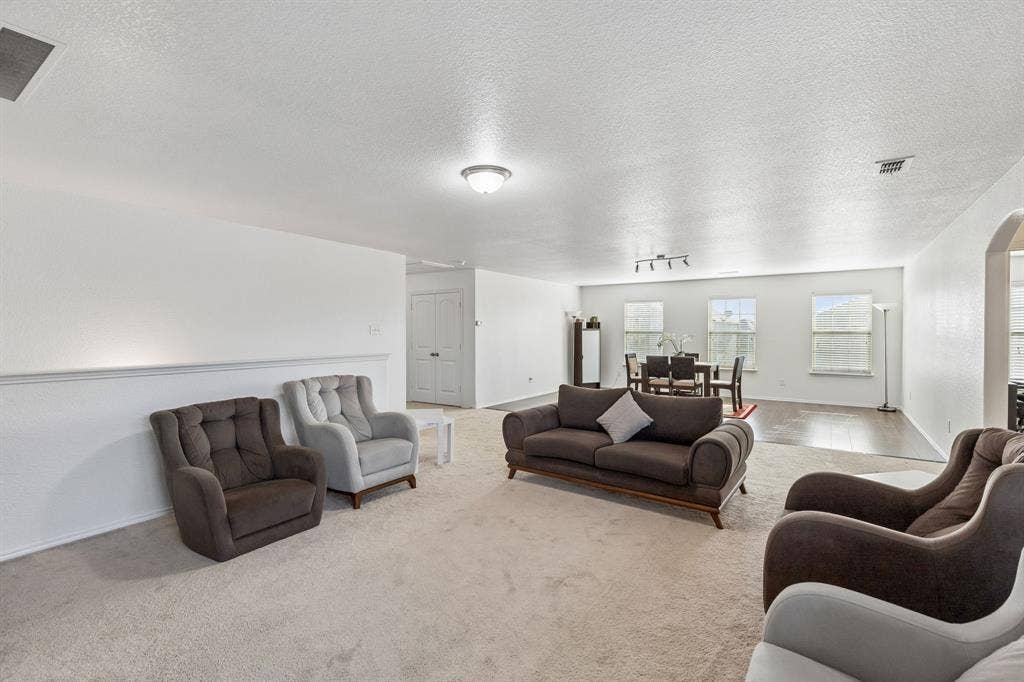 1501 Coyote Ridge Road, Wylie, TX 75098 Expansive carpeted living area with a half wall detail and overhead lighting