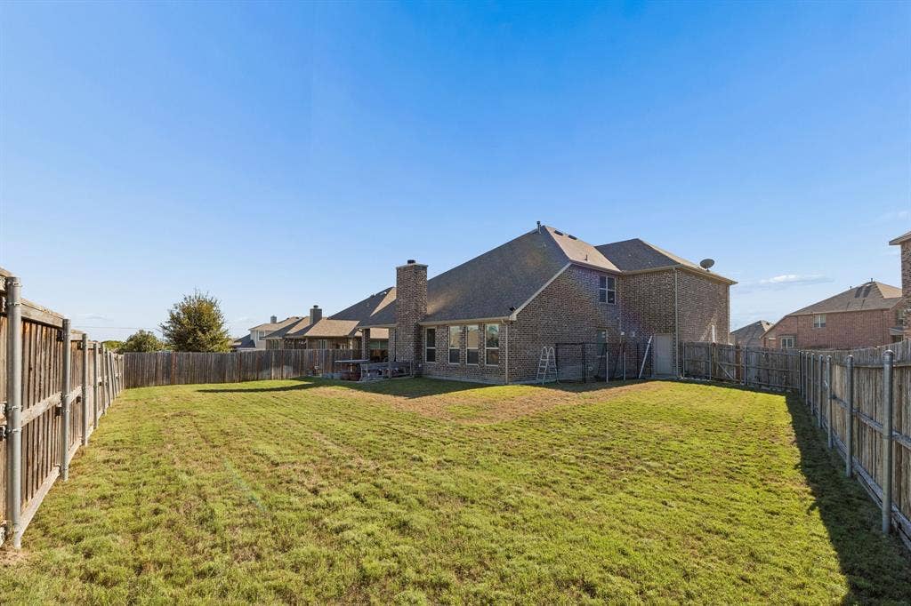 1501 Coyote Ridge Road, Wylie, TX 75098 Expansive backyard featuring a manicured lawn, full perimeter fencing, and a brick-clad exterior