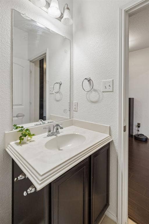 1501 Coyote Ridge Road, Wylie, TX 75098 Vanity with a white countertop and integrated sink, chrome faucet, dark wood-finish cabinetry, and a large wall-mounted mirror