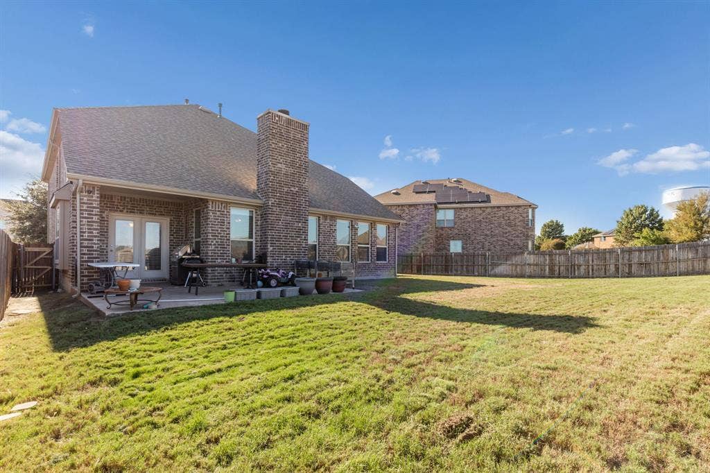 1501 Coyote Ridge Road, Wylie, TX 75098 Expansive backyard with a manicured lawn, full brick exterior, covered patio, and dual French doors