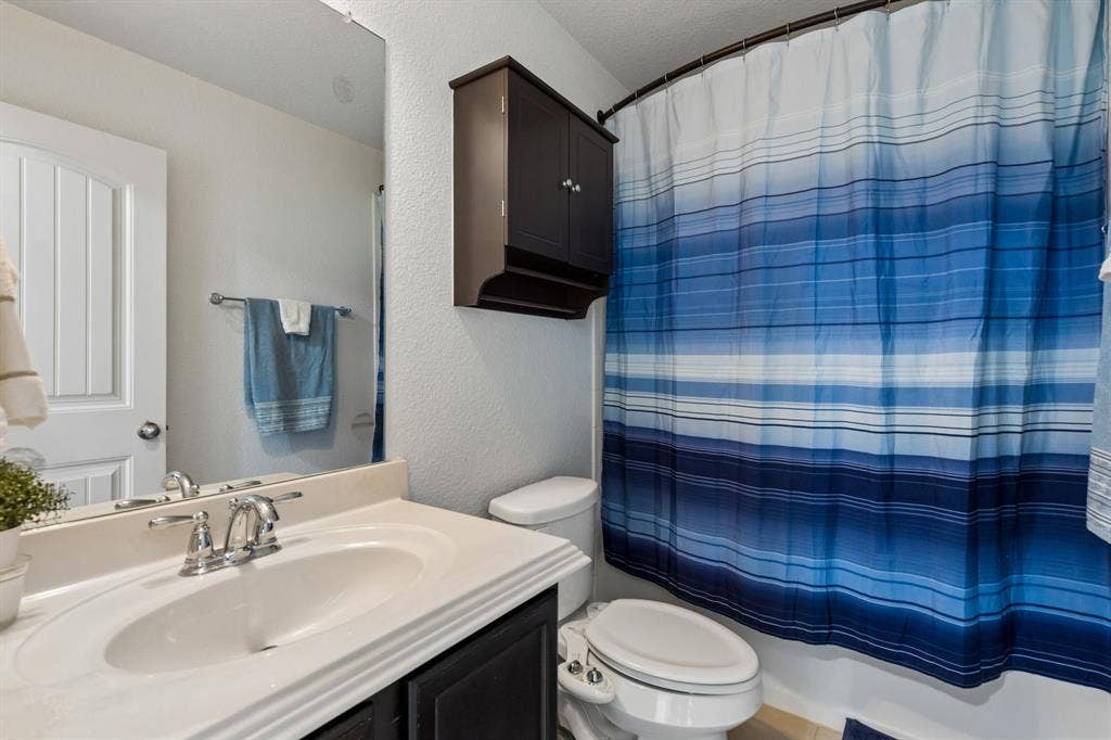 1501 Coyote Ridge Road, Wylie, TX 75098 Bathroom featuring a vanity with an integrated sink, polished chrome faucet, full-width mirror, and built-in wall cabinet