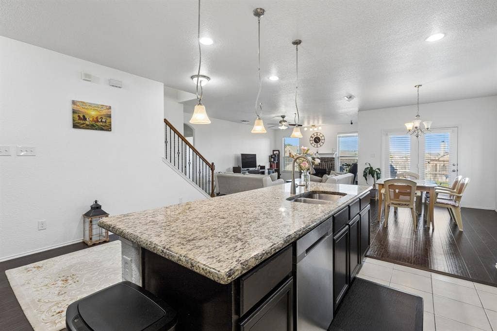 1501 Coyote Ridge Road, Wylie, TX 75098 Kitchen island featuring a granite countertop, undermount sink, and stainless steel dishwasher