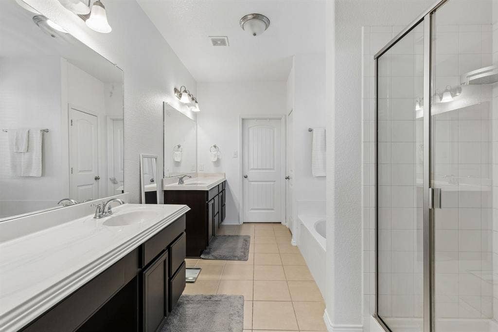 1501 Coyote Ridge Road, Wylie, TX 75098 Dual vanities with white countertops, tiled flooring, a glass-enclosed shower, and a built-in bathtub