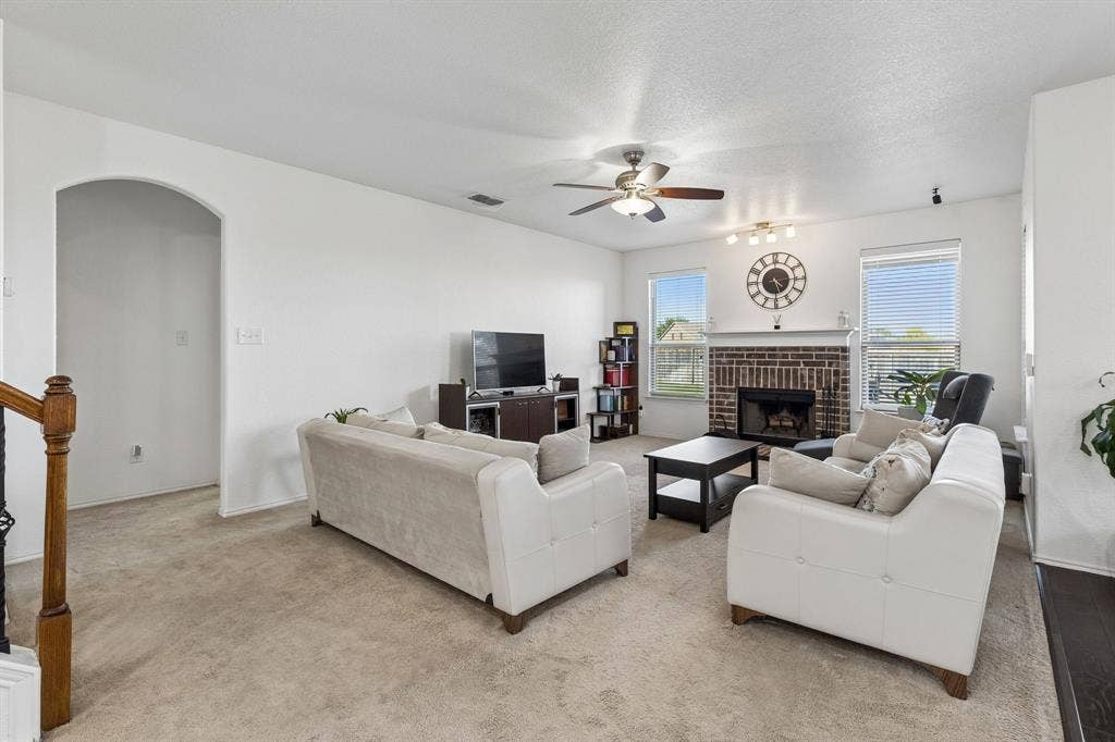 1501 Coyote Ridge Road, Wylie, TX 75098 Spacious living area featuring a brick fireplace, ceiling fan, and arched doorway