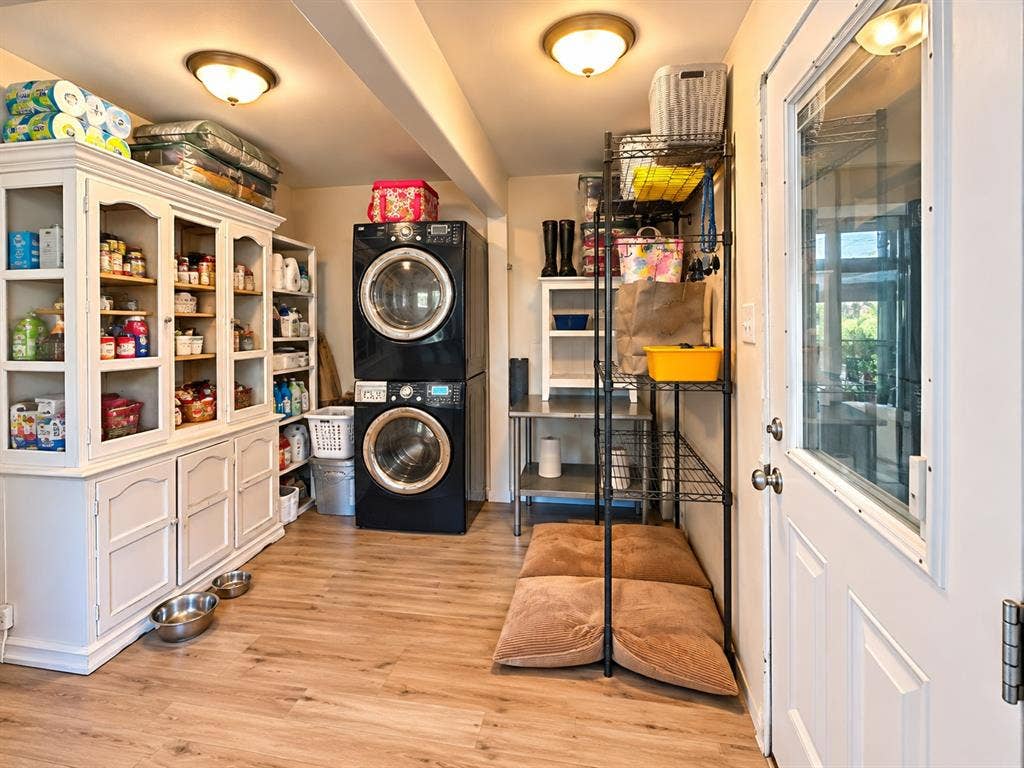 10734 Candlewood Drive, Houston, TX 77042 Utility room featuring wood-finish flooring, a white built-in storage cabinet, and a stacked washer and dryer