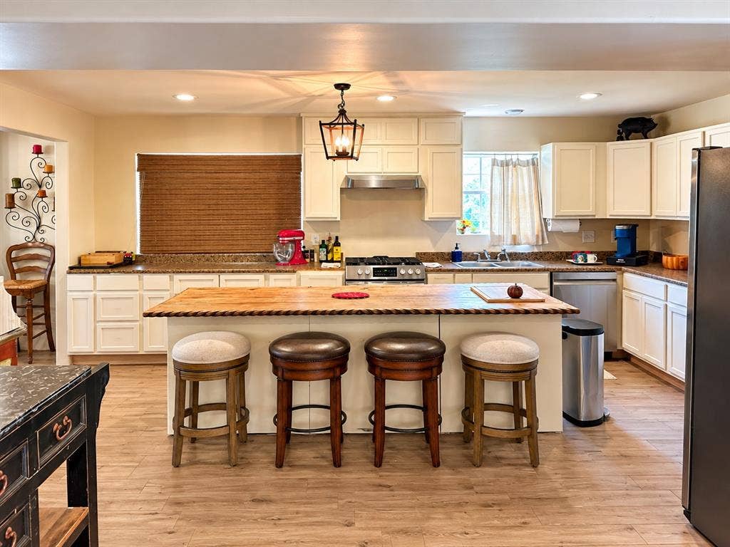 10734 Candlewood Drive, Houston, TX 77042 Kitchen featuring white cabinetry, wood-finish flooring, a central island with a wood countertop, and stainless steel appliances