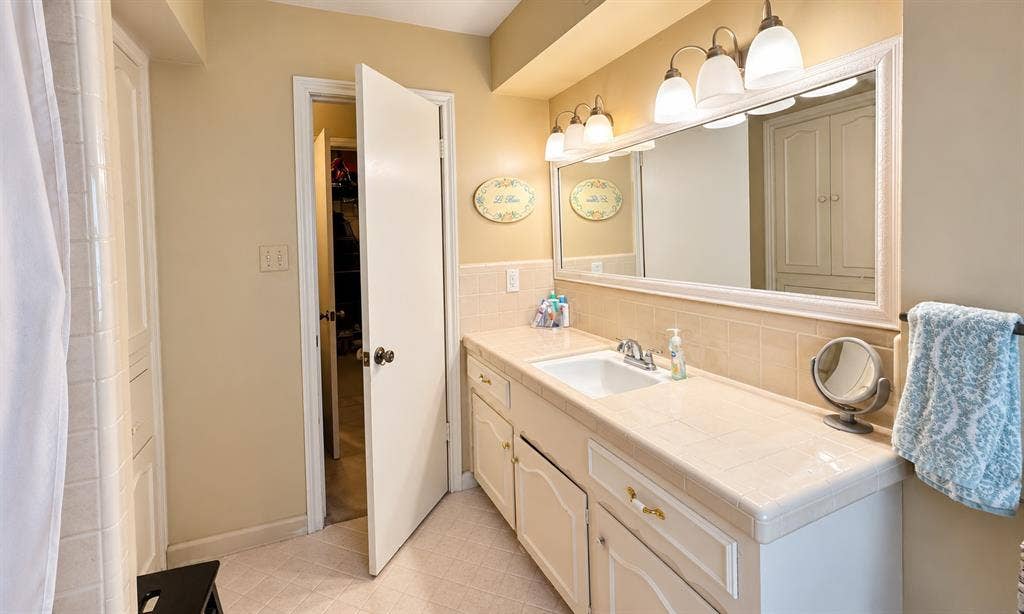 10734 Candlewood Drive, Houston, TX 77042 Vanity with integrated sink, tile countertop, and a large framed mirror