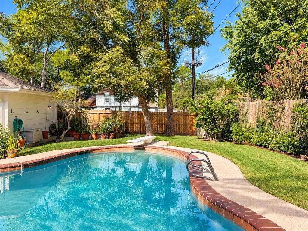 10734 Candlewood Drive, Houston, TX 77042 Curved swimming pool with a diving board, surrounded by concrete decking and a red brick coping