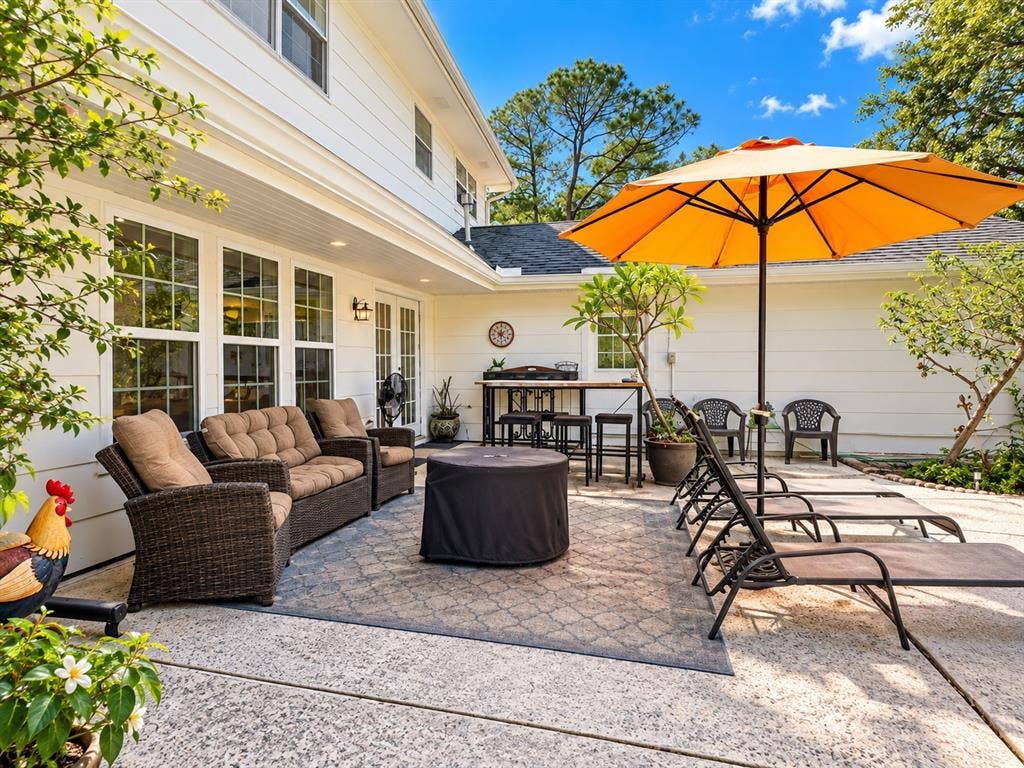 10734 Candlewood Drive, Houston, TX 77042 Expansive stamped concrete patio with multiple seating areas and direct access to the interior via French doors and large windows