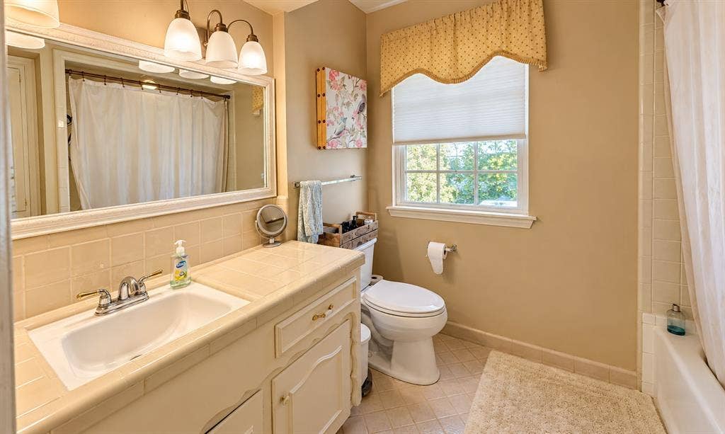 10734 Candlewood Drive, Houston, TX 77042 Built-in vanity with integrated sink, tile countertop, and wall-mounted mirror