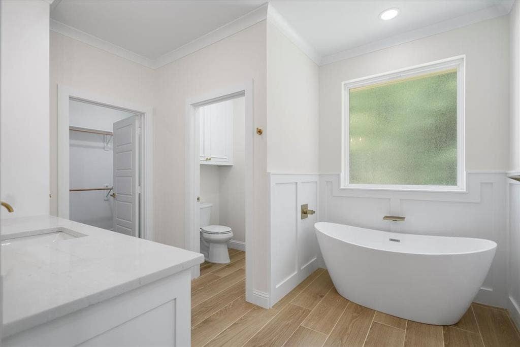 13920 Cedar Hill, Tyler, TX 75704 Freestanding bathtub with wall-mounted faucet, wood-finish flooring, white paneling, stone countertop, and recessed lighting