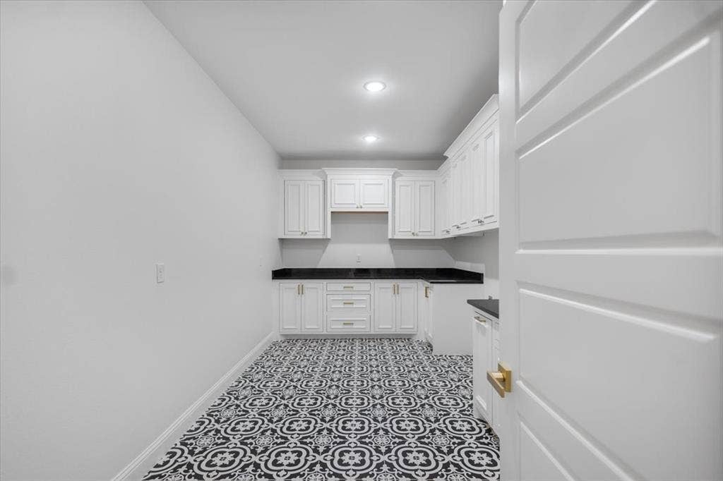 13920 Cedar Hill, Tyler, TX 75704 White shaker cabinetry, dark countertops, recessed lighting, patterned floor tile, and a paneled interior door with gold-tone hardware