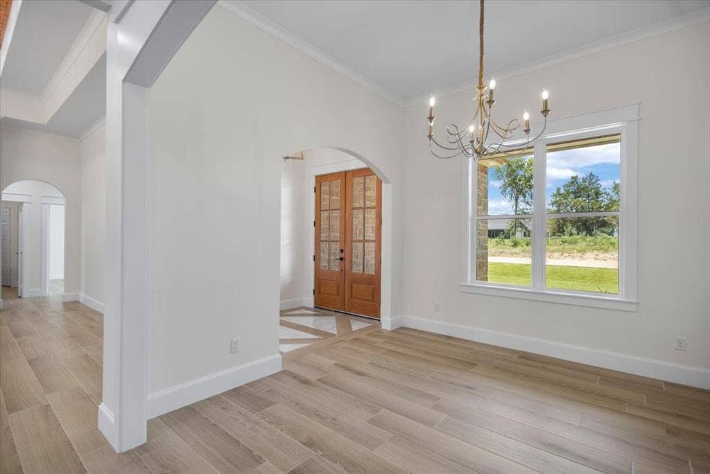 13920 Cedar Hill, Tyler, TX 75704 Wood-finish flooring, arched entryway, double-door entry with glass panels, chandelier light fixture, and white trim