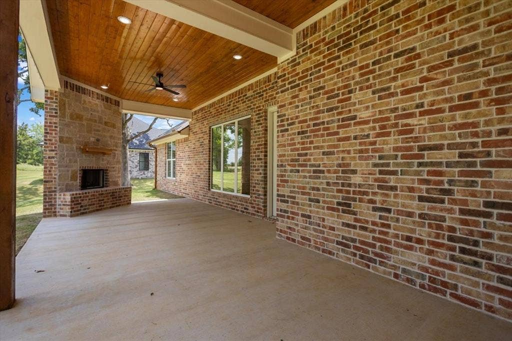 13920 Cedar Hill, Tyler, TX 75704 Covered patio with a brick and stone fireplace, wood-plank ceiling, recessed lighting, and a ceiling fan