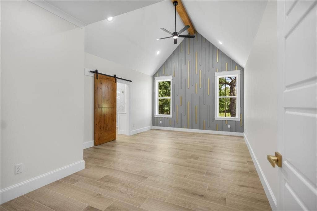 13920 Cedar Hill, Tyler, TX 75704 Vaulted ceiling with exposed wood beam, wood-finish flooring, two window openings, custom accent wall paneling, and barn door entry