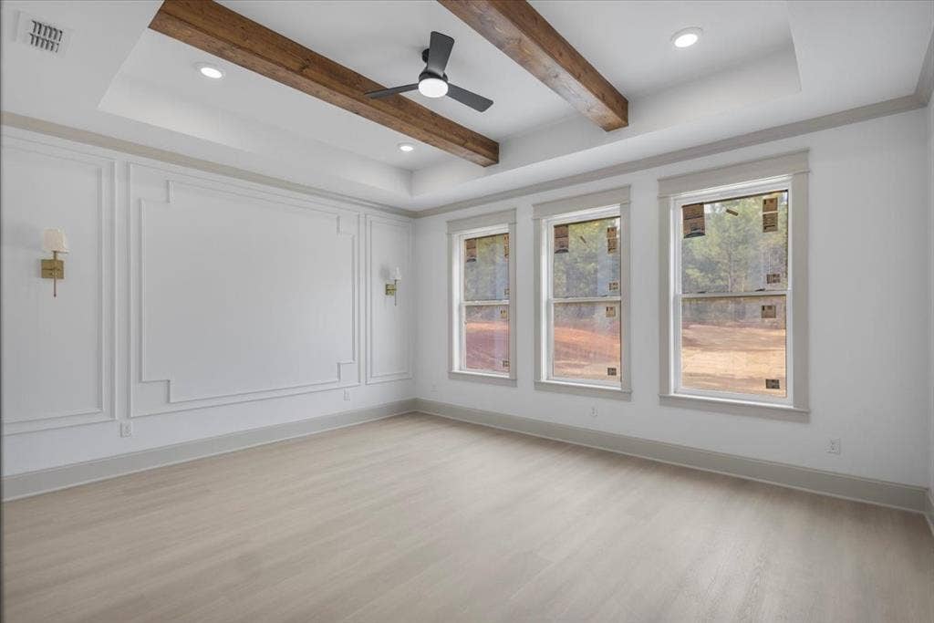 17155 Island Lake Dr., Tyler, TX 75708 Tray ceiling with exposed wood beams, recessed lighting, decorative wall molding, three windows, and wood-finish flooring