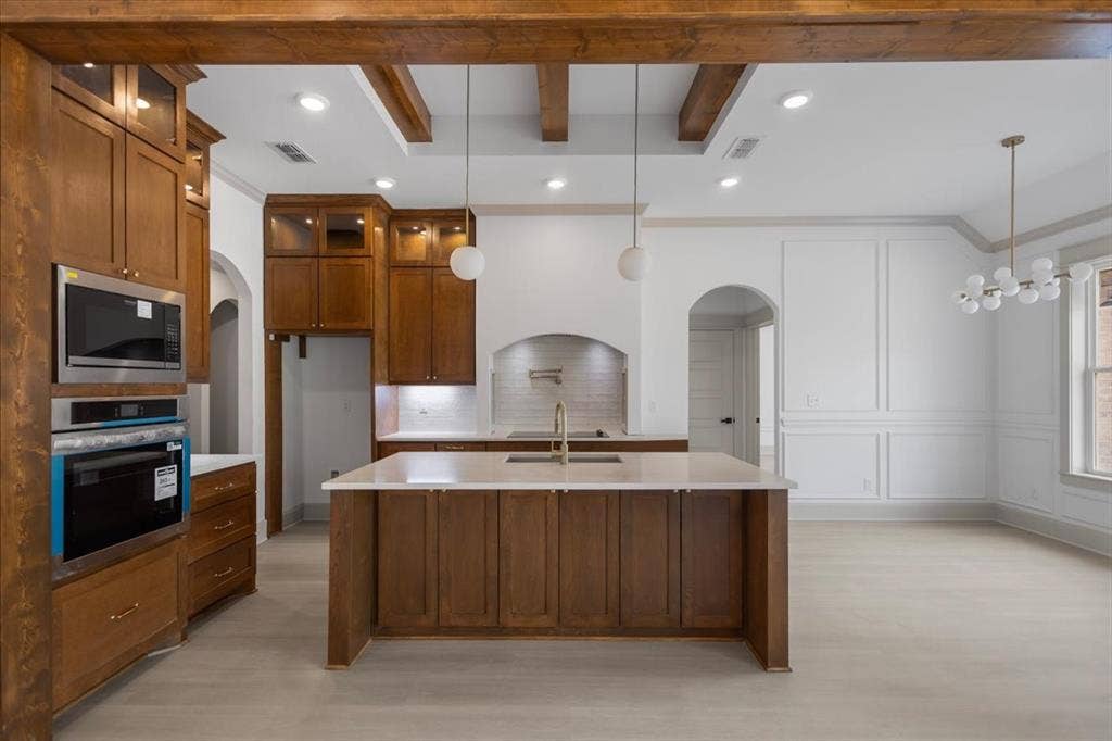 17155 Island Lake Dr., Tyler, TX 75708 Exposed wood beams, recessed lighting, integrated stainless steel appliances, central island with countertop, and decorative wall paneling