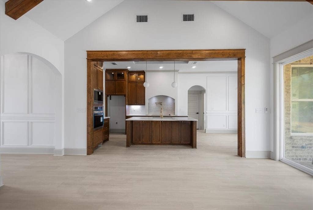 17155 Island Lake Dr., Tyler, TX 75708 Vaulted ceilings with exposed wood beams, light wood-finish flooring, built-in double ovens, and a kitchen island with integrated cabinetry