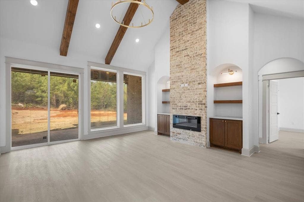 17155 Island Lake Dr., Tyler, TX 75708 Vaulted ceiling with exposed wood beams, brick fireplace with integrated insert, built-in shelving and cabinetry, recessed lighting, and wood-finish flooring