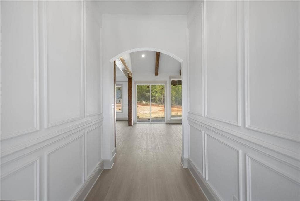 17155 Island Lake Dr., Tyler, TX 75708 Hallway featuring wainscoting, wood-finish flooring, an arched doorway, exposed ceiling beams, and a sliding glass door