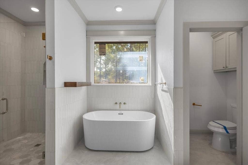 17155 Island Lake Dr., Tyler, TX 75708 Freestanding soaking tub with fluted exterior, tiled shower with glass enclosure, recessed lighting, and wall-mounted cabinetry