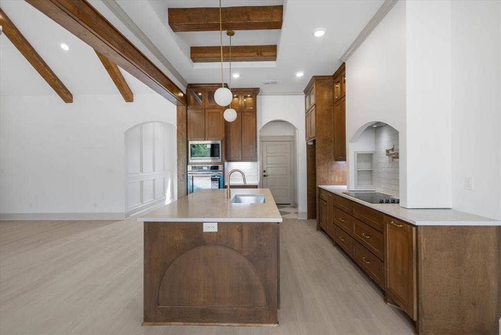 17155 Island Lake Dr., Tyler, TX 75708 Open-concept kitchen with vaulted ceiling, exposed wood beams, a spacious center island with an undermount sink, and stainless steel appliances