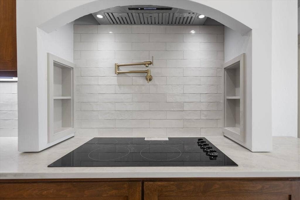 17155 Island Lake Dr., Tyler, TX 75708 Cooktop with integrated controls, wall-mounted pot filler, tile backsplash, built-in recessed shelving, and under-cabinetry