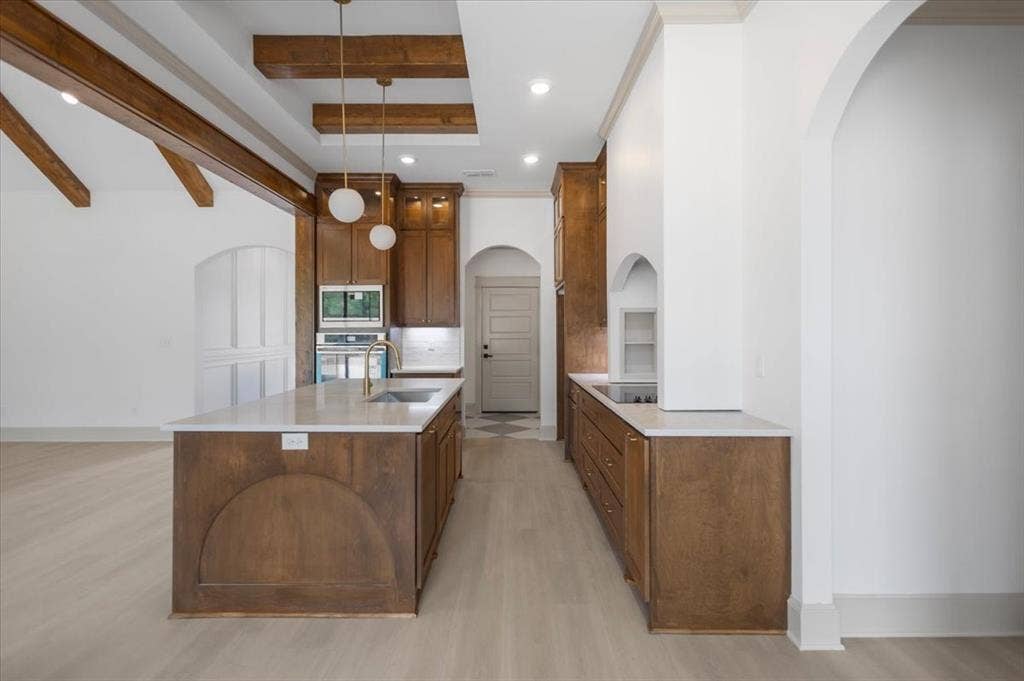 17155 Island Lake Dr., Tyler, TX 75708 Spacious kitchen with a large central island, overhead wood beams, white countertops, wood-finish cabinetry, and stainless steel appliances