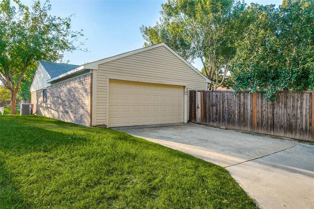 204 Timber Ridge Lane, Coppell, TX 75019 Attached two-car garage with a panel door, concrete driveway, and wood privacy fence
