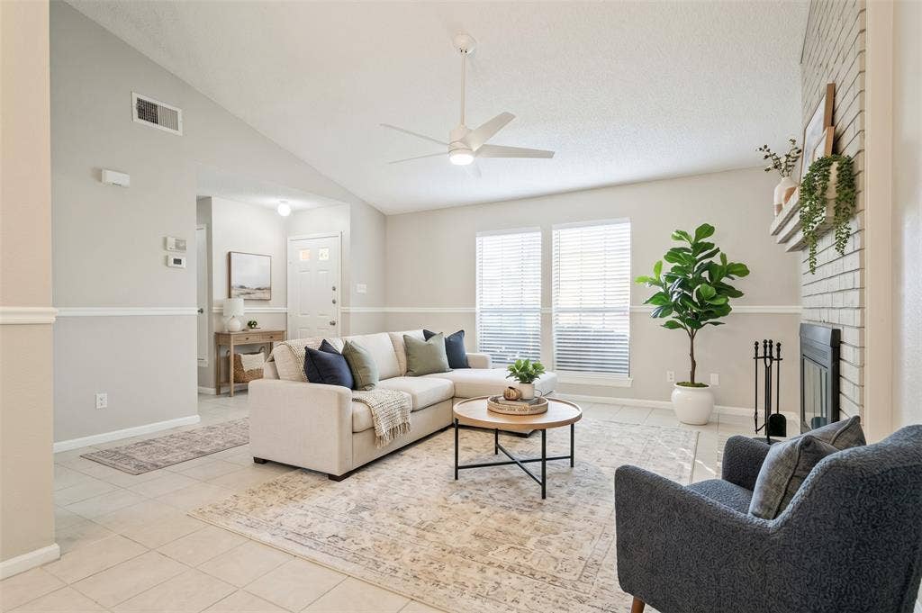 204 Timber Ridge Lane, Coppell, TX 75019 Vaulted ceiling with a ceiling fan, light-toned tiled flooring, white brick fireplace, and dual windows with blinds