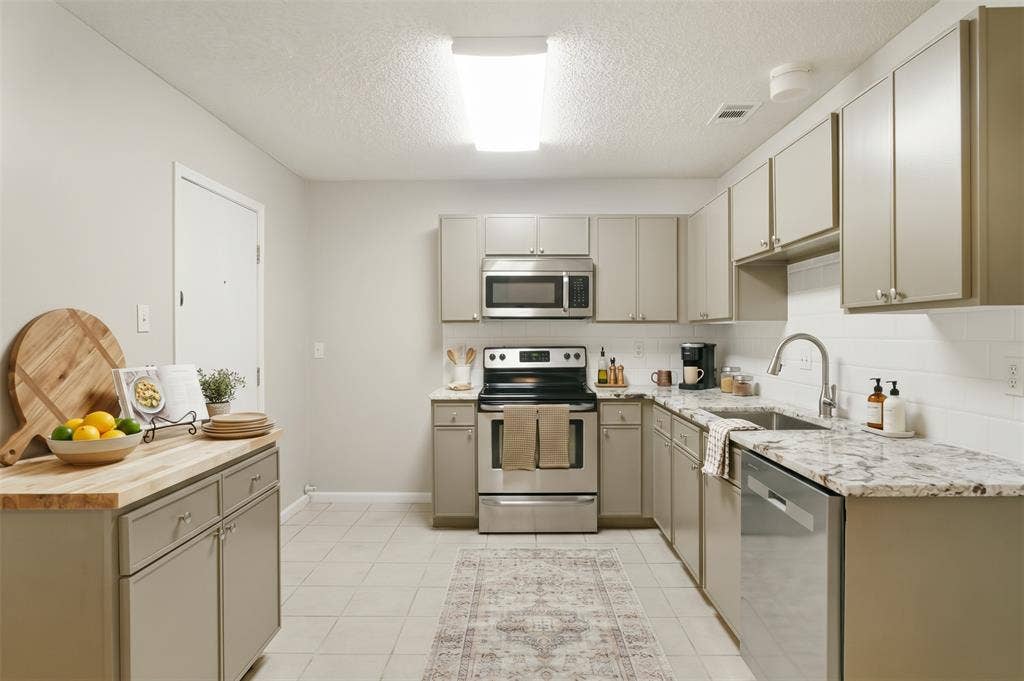 204 Timber Ridge Lane, Coppell, TX 75019 Kitchen featuring light-toned cabinetry, light-toned countertops, stainless steel appliances, a subway tile backsplash, and tile flooring