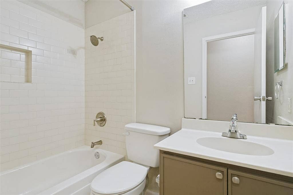 204 Timber Ridge Lane, Coppell, TX 75019 White subway tile shower surround with recessed niche, integrated bathtub, and brushed nickel fixtures