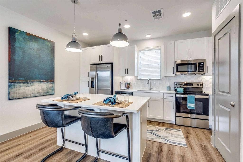 4020 McEwen Road, #9121, Farmers Branch, TX 75244 Kitchen with stainless steel appliances, decorative backsplash, white cabinetry, light wood-style floors, and recessed lighting