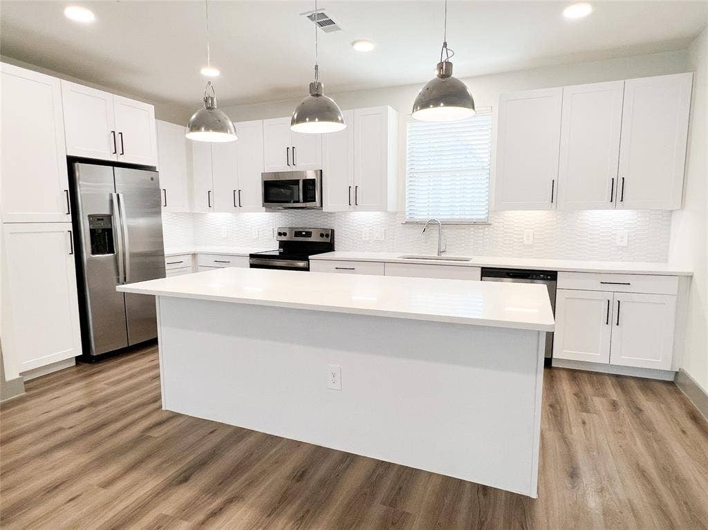 4020 McEwen Road, #8115, Farmers Branch, TX 75244 Kitchen featuring a kitchen island, hanging light fixtures, white cabinets, appliances with stainless steel finishes, and recessed lighting