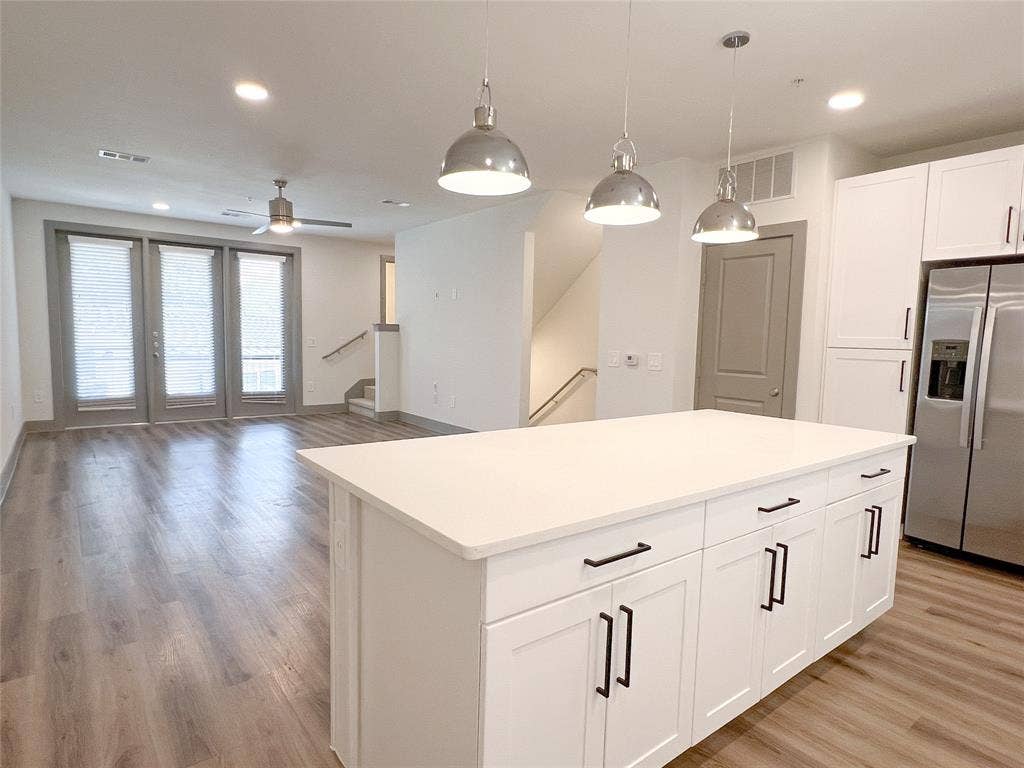 4020 McEwen Road, #8115, Farmers Branch, TX 75244 Kitchen with stainless steel fridge, hanging light fixtures, white cabinets, recessed lighting, and a center island