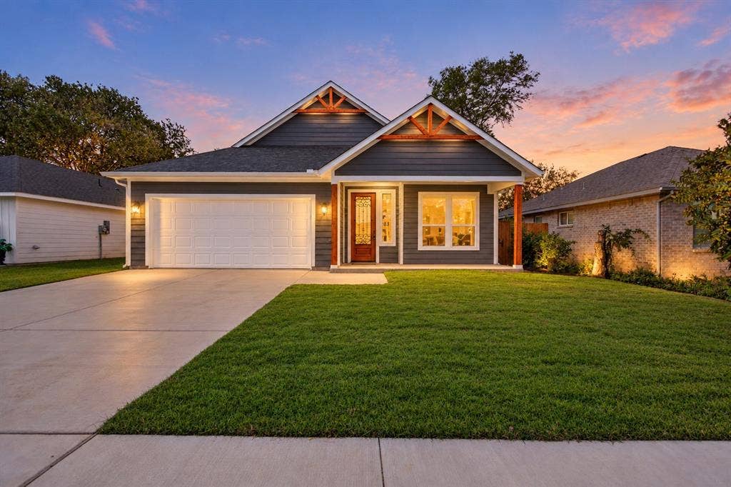 Exterior elevation featuring horizontal lap siding, a dual-gabled roofline with exposed wood trusses, a covered entry with wood-finish columns, and an attached two-car garage